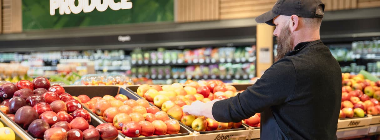 An Image of a man picking up Sobeys freshly produce fruits.